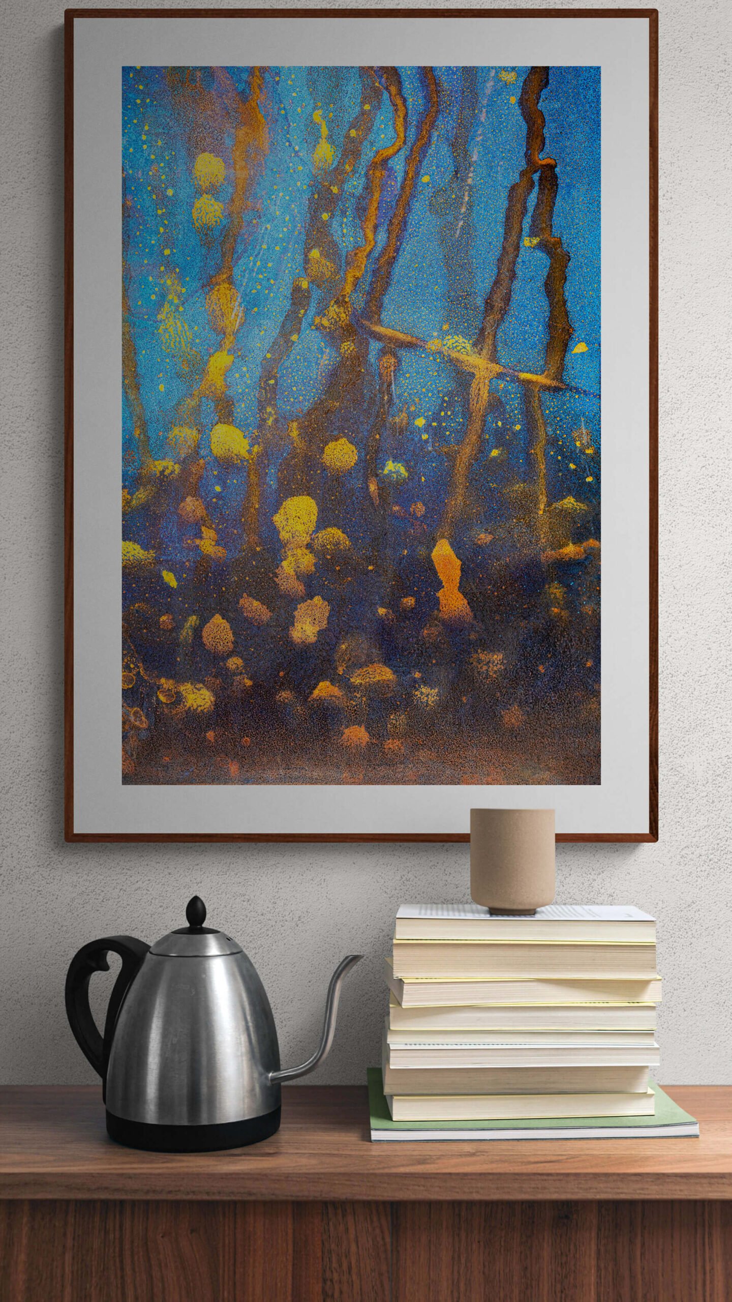 Monterey bay by Ryszard Filipowicz mockup, obraz wiszący nad komodą, na której stoi czajnik i leżą książki